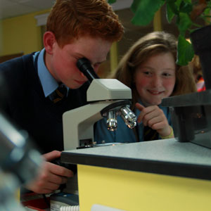 Boy and girl looking through microscope in science class