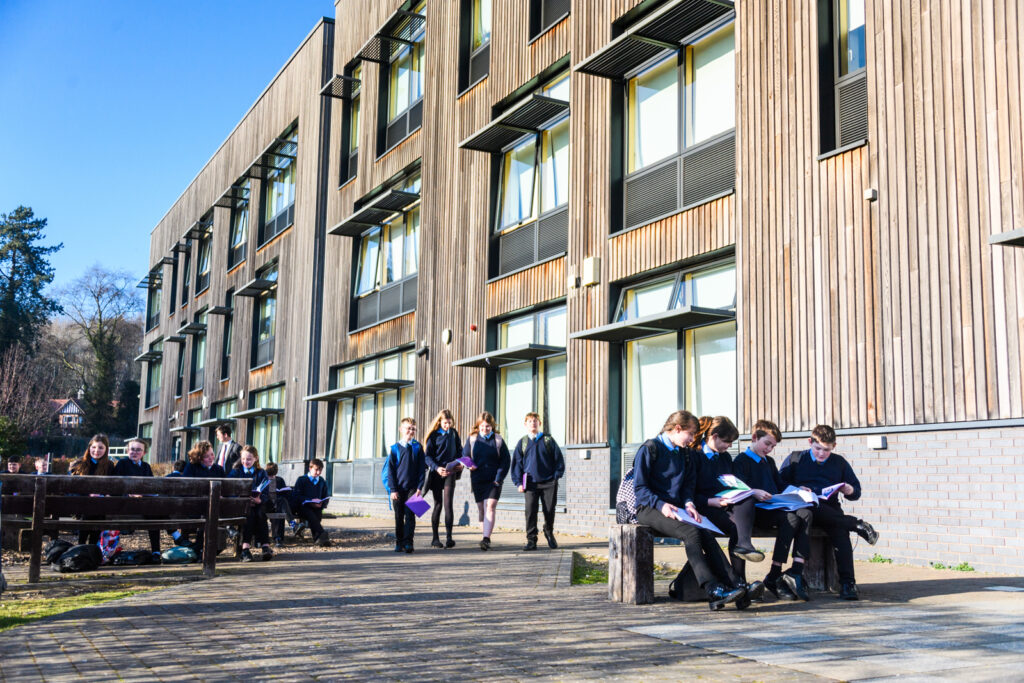 A group of students walking and holding their books, outside William Brookes School