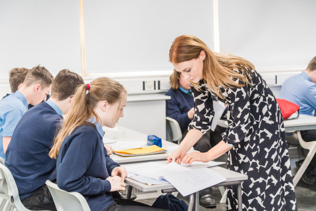 A female teacher helping a female student and other students surrounding her